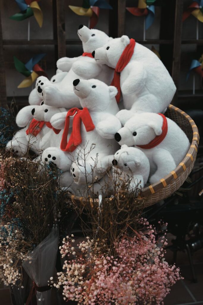 Charming display of plush polar bears in a cozy basket surrounded by dried flowers.