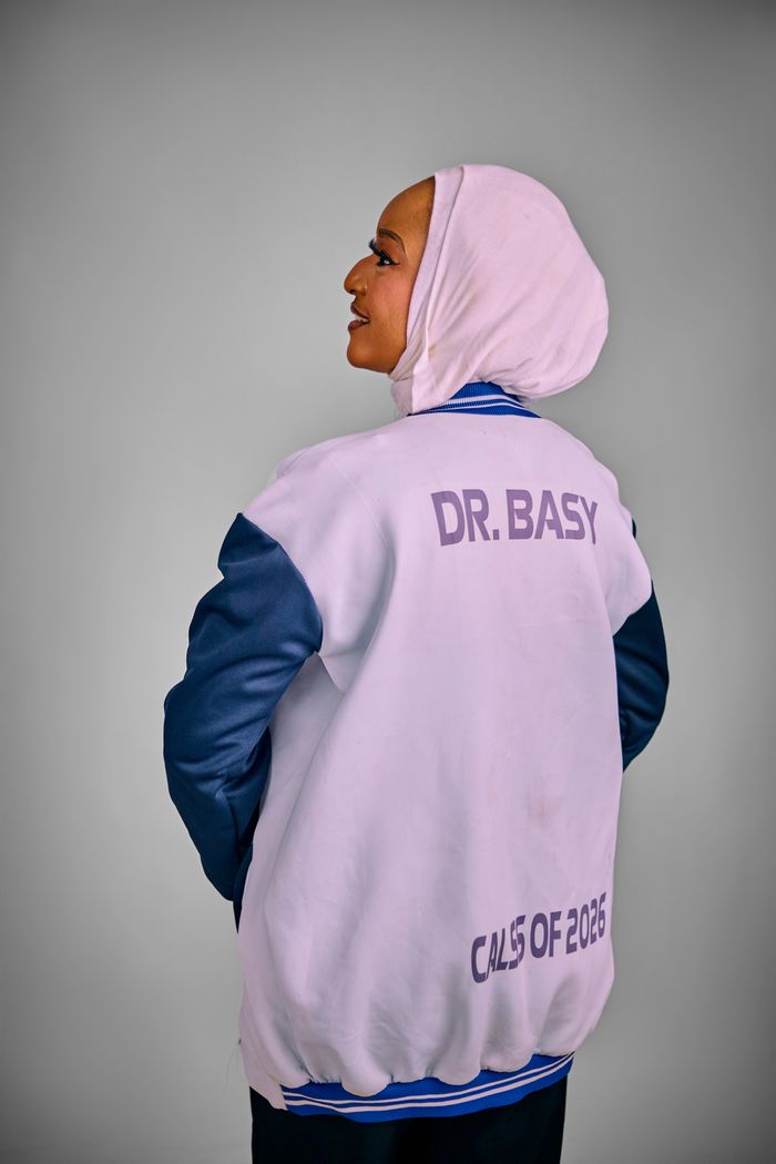 Woman in a custom jacket with 'Dr. Basy' and 'Class of 2026' text, looking confident.